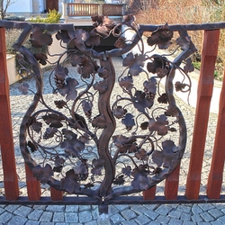 Toranlage – Wappen mit Weinrebe – handgeschmiedetes, mit Holz kombiniertes Tor an einem Einfamilienhaus