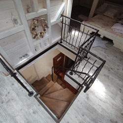 Blick auf den Zugang zum Dachgeschoss – geschmiedete Treppe mit Holzeinstiegsbrettern und Geländer