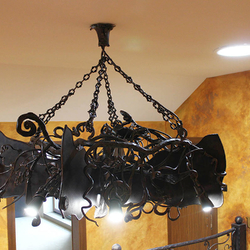 Detailansicht einer schmiedeeisernen Fledermaus über einer Galerie – majestätischer Innenkronleuchter 