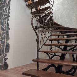 Geschmiedete Treppe mit einem außergewöhnlichen Geländer, ergänzt mit Holz – Innenarchitektur